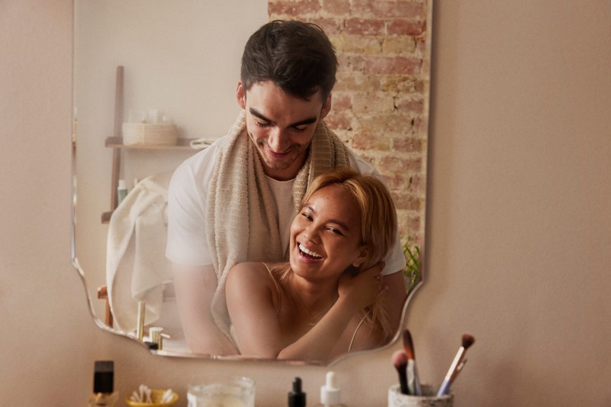 Brown haired man and blond woman standing in front of a mirror